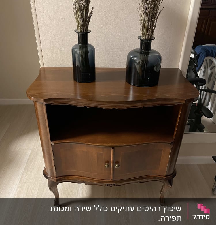 שני אגרטלים כהים עם פרחים על שידה מעץ